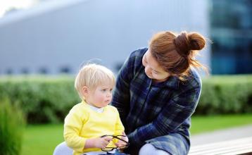 Child care provider caring for toddler boy sitting outside