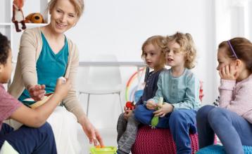 Children in a daycare setting sitting with their child care provider
