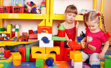 Two young girls playing with colorful building blocks
