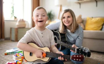 Early educator playing guitar with child