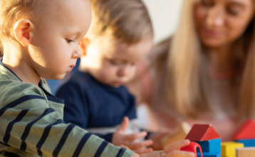 Toddlers playing blocks with a child care provider.