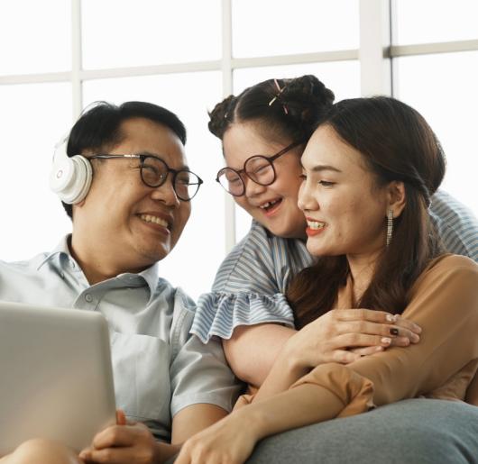 Happy family of three sitting together on couch with laptop.