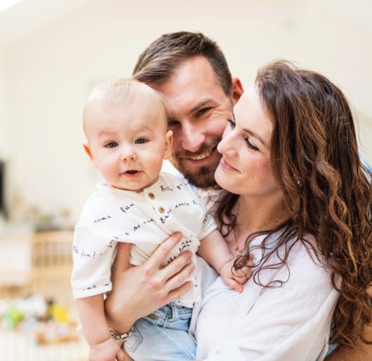 Young family holding their baby boy at home.