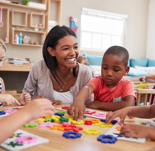 A group of students doing an activity with their teacher at the table. 