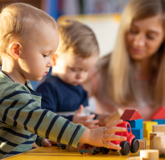 Toddlers playing blocks with a child care provider.