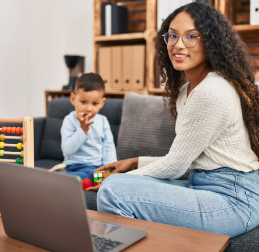 Woman smiling working with child and computer