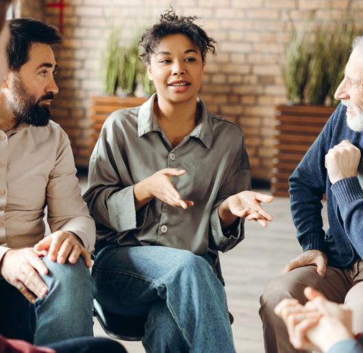 Individuals sitting in a circle having a discussion.