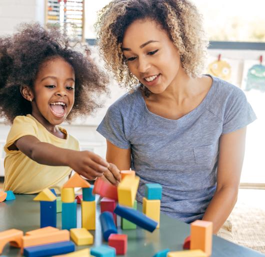 Mom and toddler play with colorful wooden blocks
