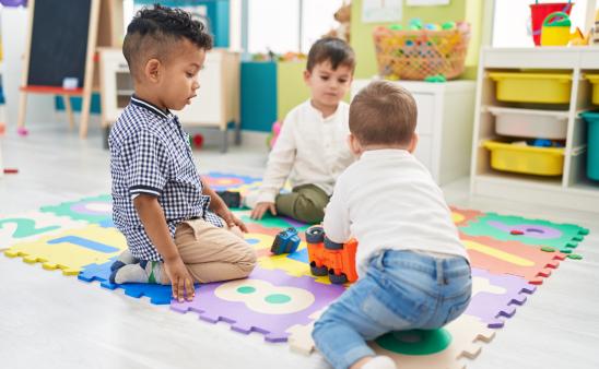 Group of kids playing with cars toys sitting on floor at kindergarten.