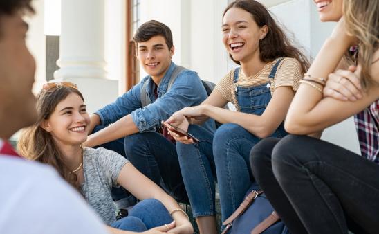 A group of teenagers sitting together outside.