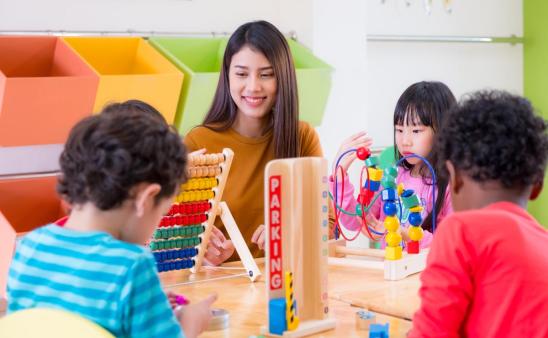 Teacher in a child care setting learning and playing with three children