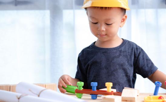 Young boy wearing a construction hat playing with tools