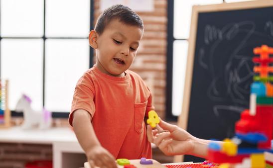 A child completes a puzzle of wooden numbers