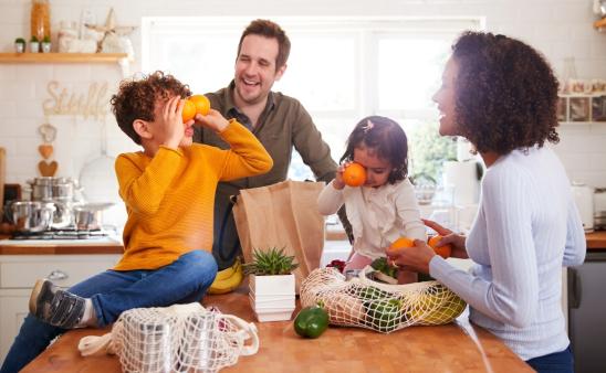 Family smiling around groceries in a kitchen