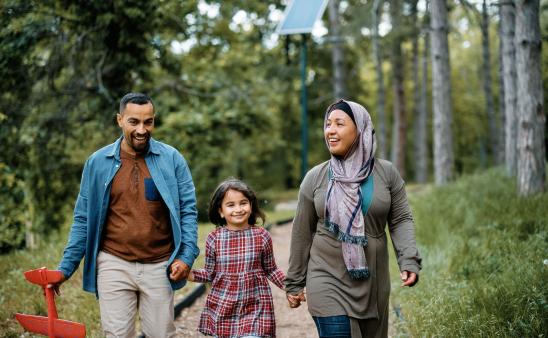 Mom, dad, and girl walk on a trail. Dad is holding a toy airplane.