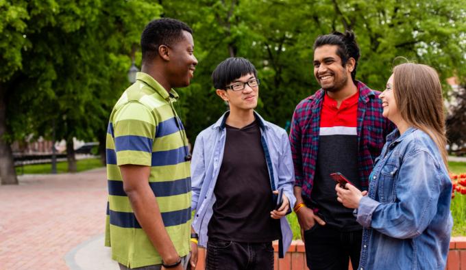 A group of college students converses outdoors.