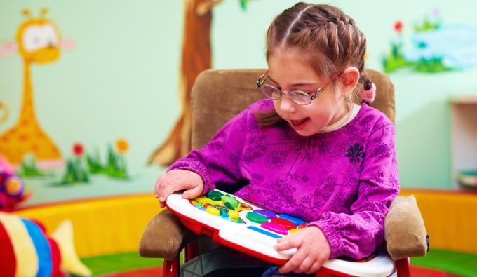 A girl with special needs playing with an educational toy.