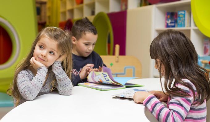 Preschool age kids looking through books in a classroom setting