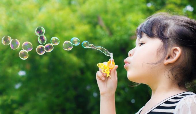 Young girl blowing bubbles outside 
