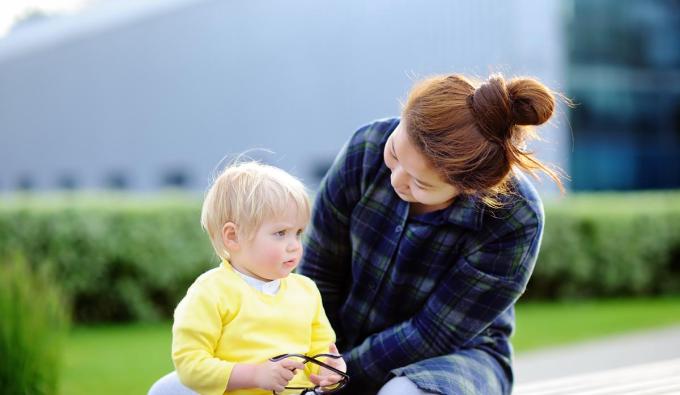 Child care provider caring for toddler boy sitting outside