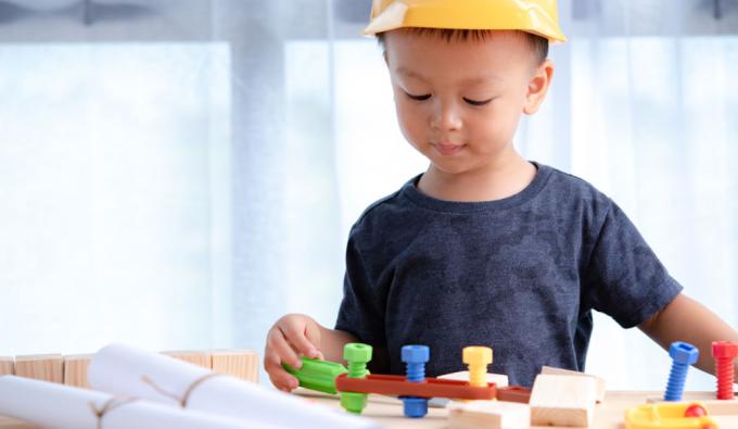 Young boy wearing a construction hat playing with tools