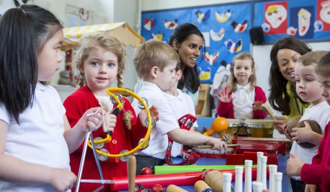 Two child care providers playing musical instruments with children