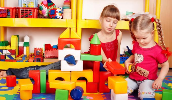 Two young girls playing with colorful building blocks