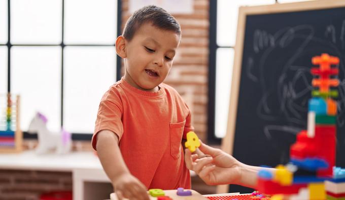A child completes a puzzle of wooden numbers