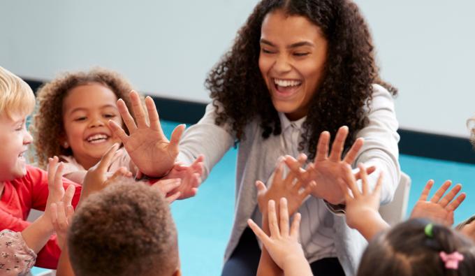 A smiling teacher high fives her students
