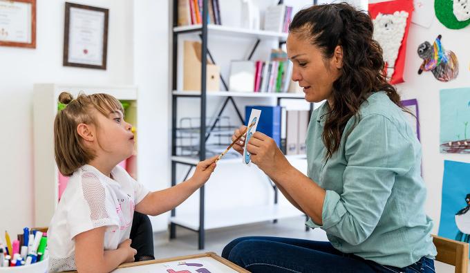 Child points to a number flashcard held by a screener