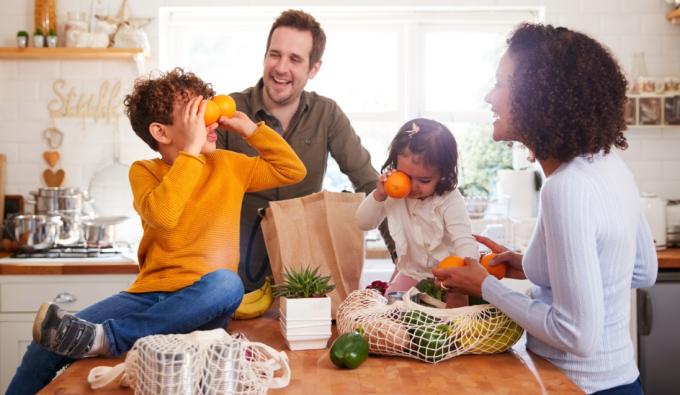 Family smiling around groceries in a kitchen