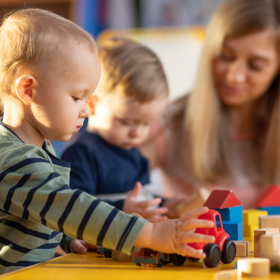 Toddlers playing blocks with a child care provider.