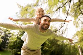 Child on dad's back, both pretending to be airplanes