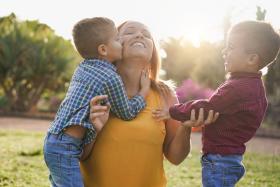 Boy kisses mom's cheek and his brother smiles