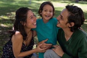 Mom, dad and preschooler laughing outside