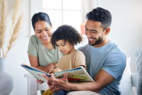 Dad reading a book to a young child while mom looks on