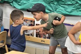 Preschooler holding off another kid who wants his toy