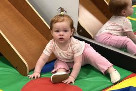 Baby on a soft mat next to a wooden slide