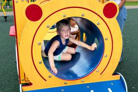 Boy crawls through a tunnel at the park