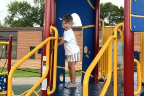 Boy standing at the top of the stairs on the jungle gym