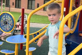 Blond boy goes down the jungle gym stairs