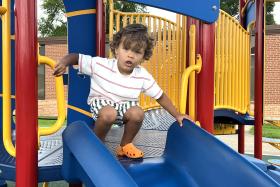 Boy squats at the top of a blue slide