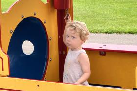Child stands in a train structure at the playground