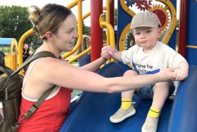 Mom helps a toddler down the slide