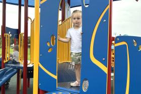 Child peeks out between two walls on the jungle gym