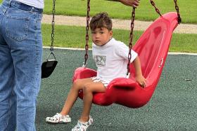 Boy sits in a red swing