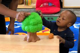 Baby touching a plastic tree toy