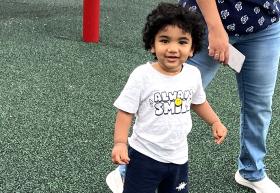 Smiling boy on the playground wearing a shirt that says "always smile"