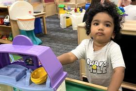 Toddler standing by a toy house