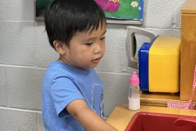 Toddler plays in a toy kitchen